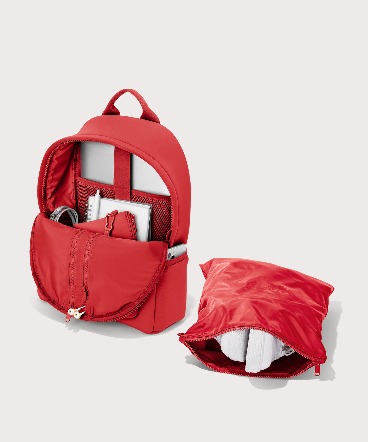 Dagne Dover Medium Dakota Backpack in a fiery, saturated red leaning toward orange unzipped, showing the interior pockets and shoe bag.