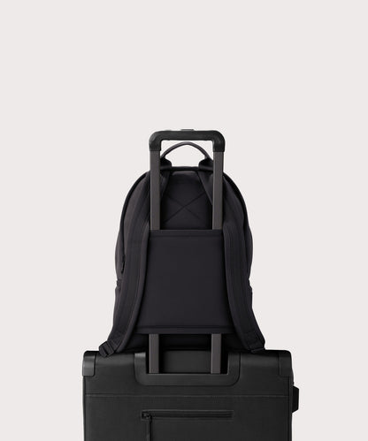 Dagne Dover medium Dakota Neoprene Backpack in onyx strapped to luggage with the neoprene luggage-handle sleeve