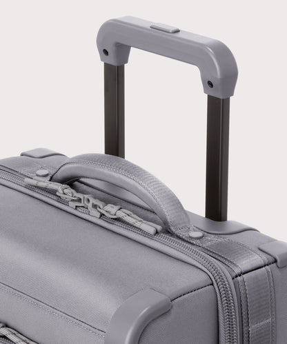 Detail shot of Seattle carry-on rolling luggage 23.5” in light grey extended luggage handle and puffy handle